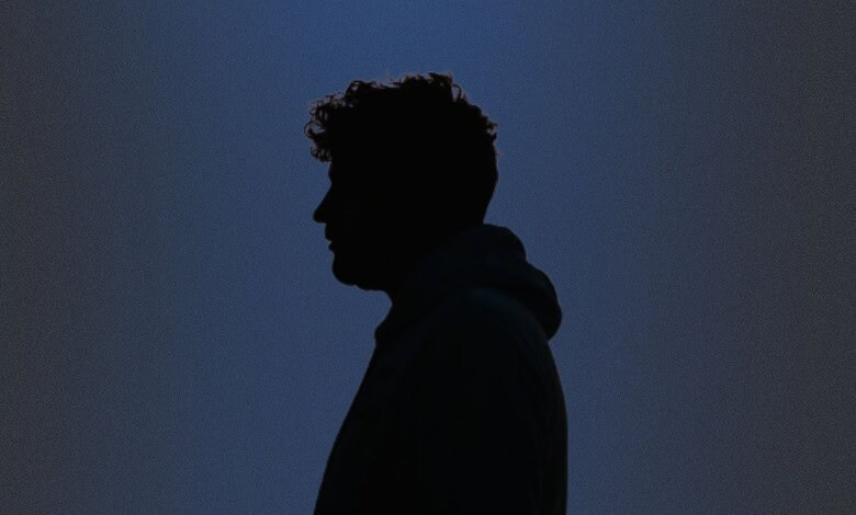 Silhouette of a young man against a dark blue background.