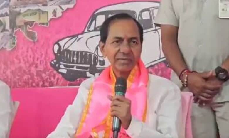 KCR speaking at an event with a pink backdrop and a drawing of a car.