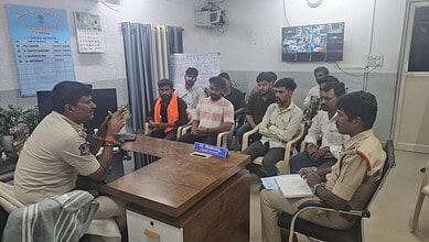 Police officer addressing a group of people in a meeting room during Ganesh festival.