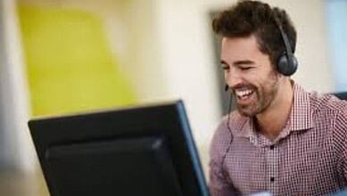Happy man with headset working at computer for The Siasat Daily news.