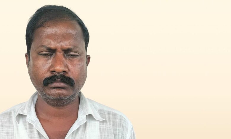 Man with a serious expression, dark hair, and a white shirt against a plain background.