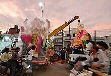 Giant Ganesh idol being installed during Ganesh Chaturthi celebrations in a busy street.