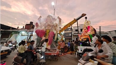 Giant Ganesh idol being installed during Ganesh Chaturthi celebrations in a busy street.
