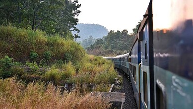 Passenger train traveling through lush green landscape near Yeshwanthpur to Bidar route.
