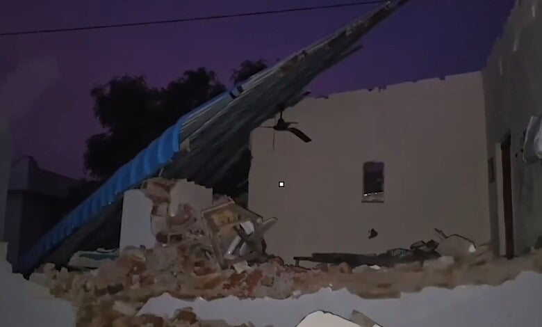 Collapsed building with debris after demolition, dark sky in background.