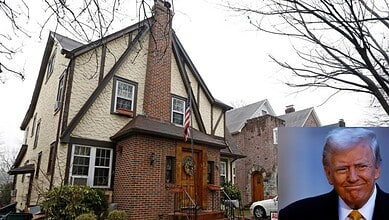 Historic brick and stucco house with American flag and leafless trees in front.