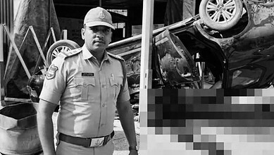 Police officer at the scene of a car accident with an overturned vehicle in black and white.