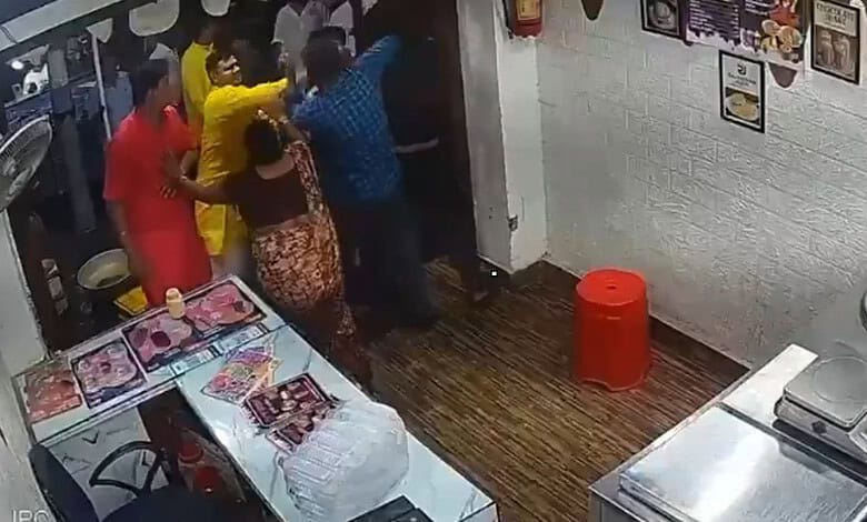 People involved in a physical altercation inside a small shop or restaurant.