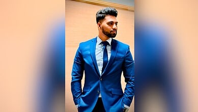 Young man in a blue suit looking to the side against a wooden background.