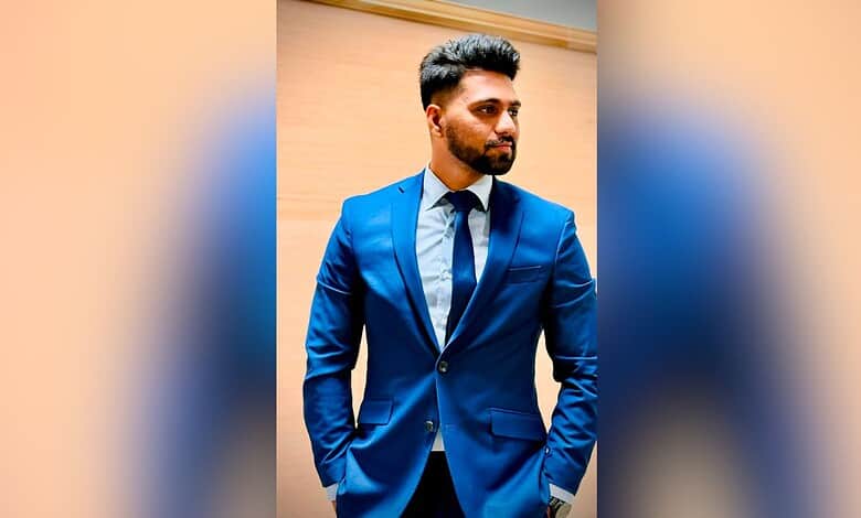 Young man in a blue suit looking to the side against a wooden background.