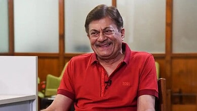 Actor Anant Nag smiling in a red shirt during an interview or event.