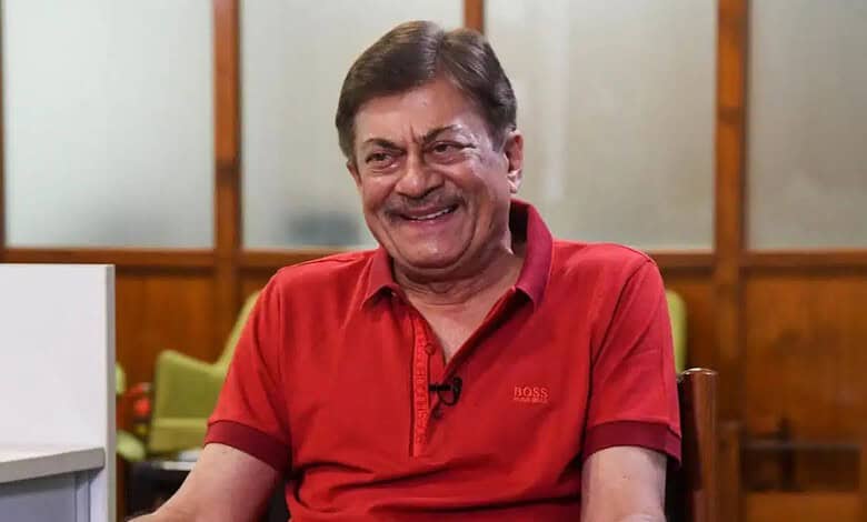 Actor Anant Nag smiling in a red shirt during an interview or event.