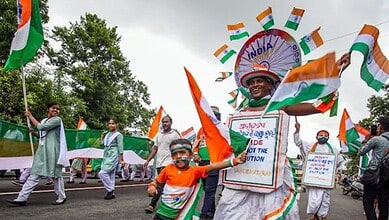 Indian independence march with children and adults holding flags and banners.
