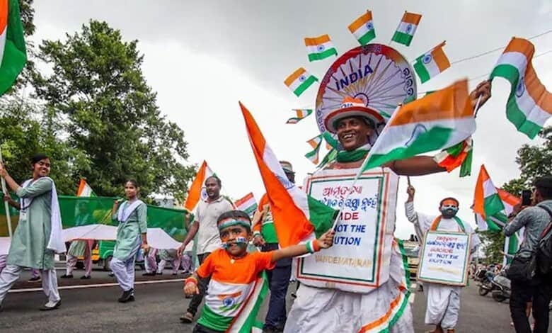 Indian independence march with children and adults holding flags and banners.