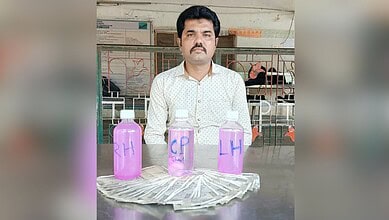 Man sitting behind bottles labeled 'RA', 'CP', and 'LH' with cash in front, in an indoor setting.