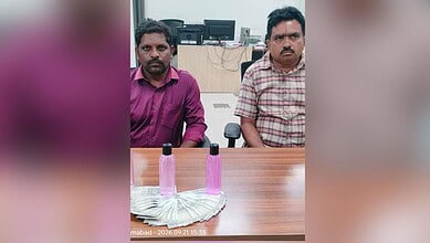 Two government officials detained in Nizamabad for Rs 15,000 bribe, seated at a table.