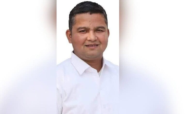Portrait of a smiling man in a white shirt against a plain background.
