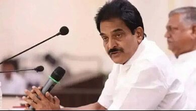 Indian politician speaking at a press conference with microphones in front.