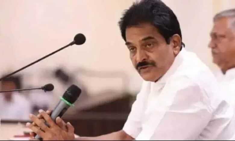 Indian politician speaking at a press conference with microphones in front.