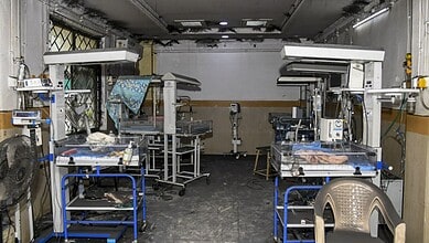 Empty hospital operating room with surgical tables and equipment.