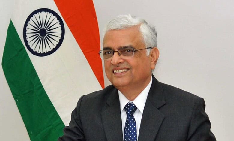 Former CEC O P Rawat smiling with Indian flag in background.