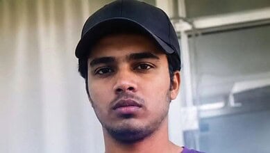 Young man with serious expression wearing a black cap indoors.