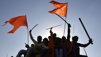 Group of people holding orange flags and swords against a clear sky.