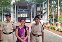 Two police officers and a woman in a purple saree standing outside a government building in Hyderabad.