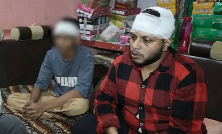 Man with bandaged head sitting with a young boy in a shop with stacked goods behind them.