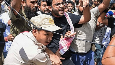 Protesters clash with police during a demonstration, holding banners and raising voices.