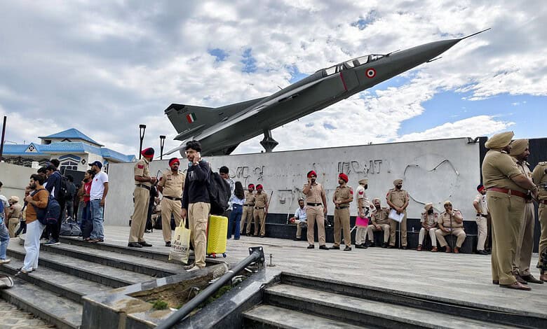 Indian Air Force fighter jet displayed at a public event with police and civilians nearby.