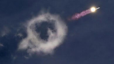 Rocket launch with smoke ring formation in the sky during SpaceX's Starship mission.