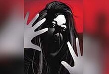Woman with long hair pressing hands against glass with a red background.