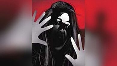 Woman with long hair pressing hands against glass with a red background.