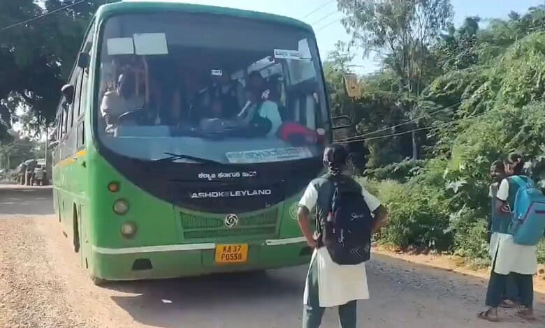 Green and black Ashok Leyland bus on rural road with students boarding in Karnataka.