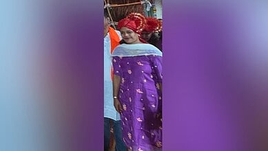 Woman in traditional purple attire and red headscarf at a cultural event in Hyderabad.