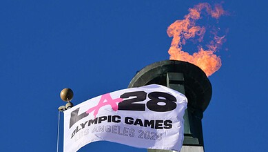 Olympic torch with flame burning atop a tower during the 2028 Los Angeles Games.