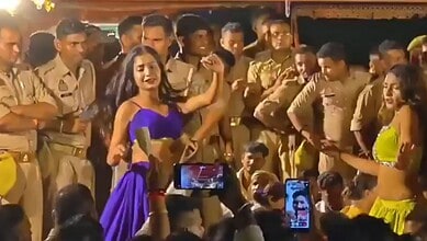 Women dancing in front of police officers during a public event in India.