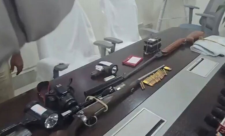 Collection of firearms, ammunition, and related equipment on a conference table.