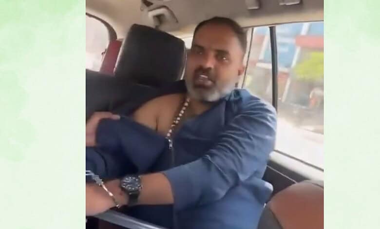 Man with a beard and traditional attire sitting in a vehicle, looking towards the camera.