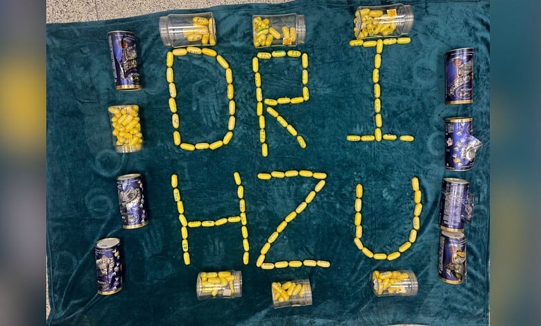 Creative arrangement of yellow and purple cans spelling 'DRI HZU' on a teal surface.
