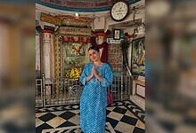 Uorfi Javed in a blue traditional dress praying inside a temple with religious decorations.