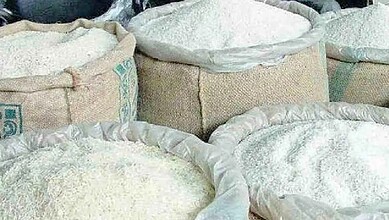 Bags of rice stacked in a storage facility, ready for distribution or sale.