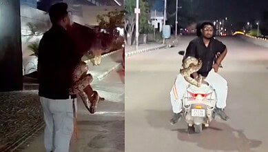 Man riding a scooter with a child at night near Durgam Cheruvu, Hyderabad.