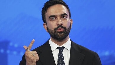 Man in suit gesturing with his index finger against a blue background.