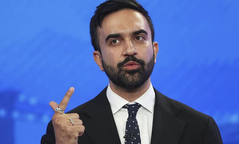 Man in suit gesturing with his index finger against a blue background.