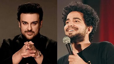 Adnan Sami performing on stage with a microphone, smiling and engaging the audience.