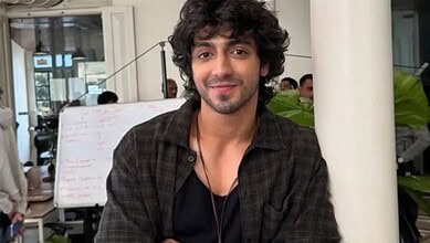 Ahaan Panday with curly hair and a beard, smiling in a casual setting.