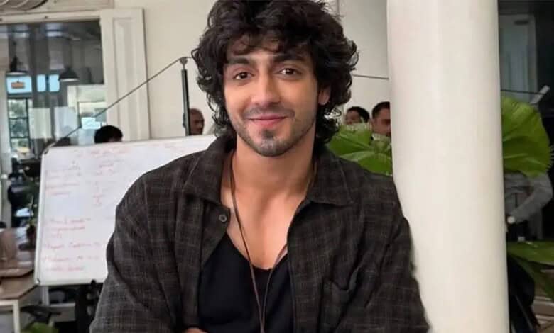 Ahaan Panday with curly hair and a beard, smiling in a casual setting.