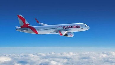 Air Arabia passenger aircraft flying above clouds.